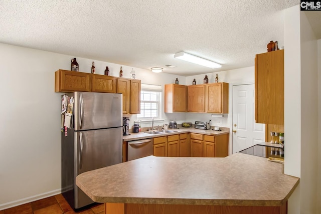 kitchen with stainless steel appliances, dark tile flooring, a textured ceiling, sink, and kitchen peninsula