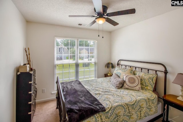 bedroom with a textured ceiling, carpet, and ceiling fan