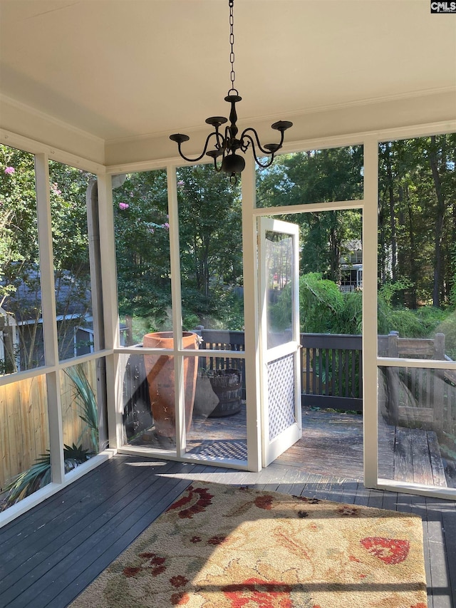 unfurnished sunroom featuring a healthy amount of sunlight and a notable chandelier