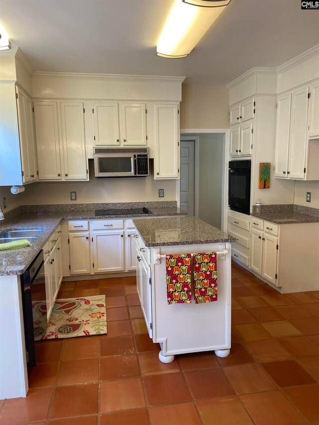 kitchen featuring oven, white cabinetry, dark tile floors, a center island, and dark stone counters