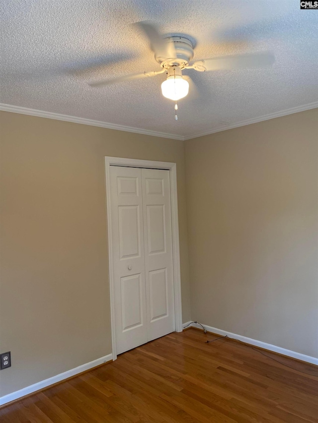 unfurnished bedroom with ceiling fan, a textured ceiling, ornamental molding, a closet, and dark hardwood / wood-style flooring