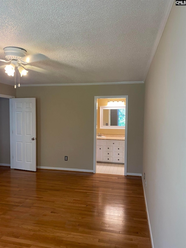 empty room with ceiling fan, a textured ceiling, light hardwood / wood-style flooring, crown molding, and sink