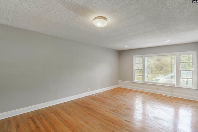 empty room with a textured ceiling and light hardwood / wood-style floors