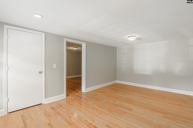 unfurnished room featuring a textured ceiling and light hardwood / wood-style flooring