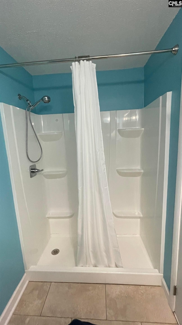 bathroom featuring tile floors, a shower with shower curtain, and a textured ceiling