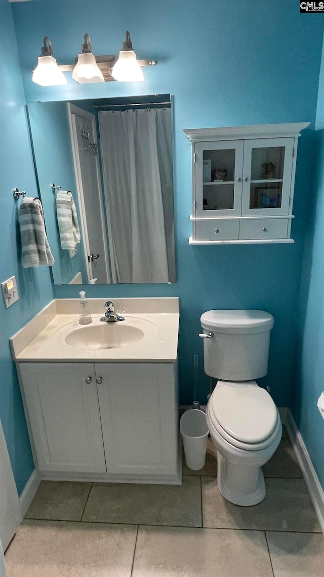 bathroom with tile flooring, toilet, and vanity