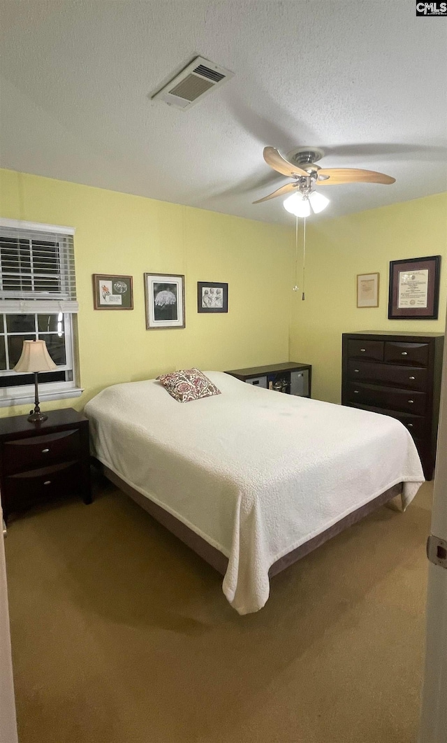 bedroom with ceiling fan, a textured ceiling, and carpet flooring