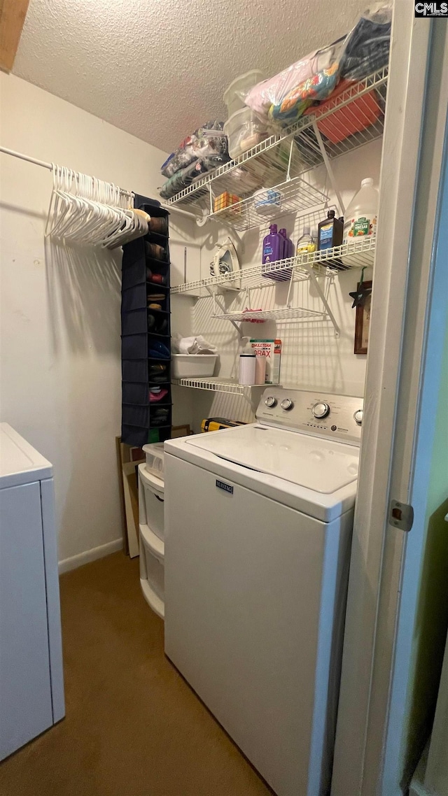 clothes washing area featuring carpet floors, a textured ceiling, and washer and clothes dryer