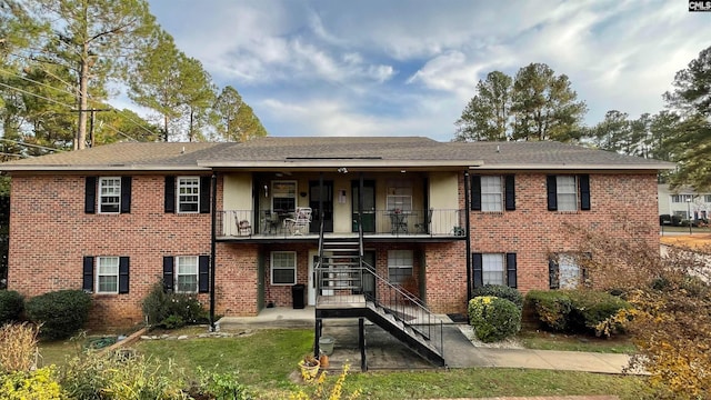 view of front of property featuring a balcony and a front lawn