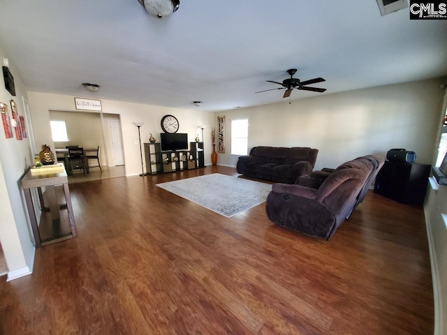 living room with dark wood-type flooring and ceiling fan