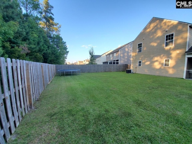 view of yard with a trampoline and central air condition unit