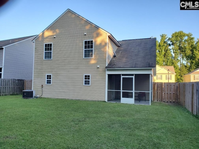 back of property with a yard, a sunroom, and central AC