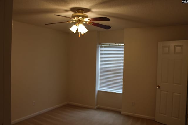 spare room featuring ceiling fan, light carpet, and a textured ceiling