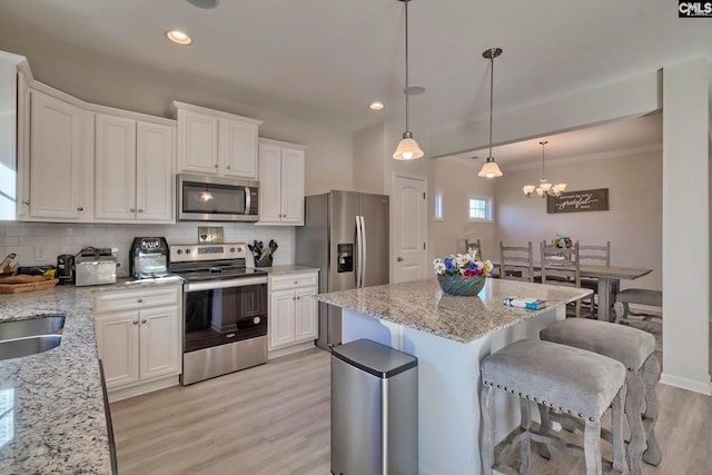 kitchen featuring light wood-type flooring, tasteful backsplash, stainless steel appliances, a chandelier, and white cabinets