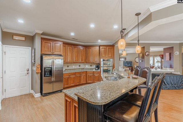 kitchen with light wood-type flooring, a breakfast bar area, appliances with stainless steel finishes, and sink