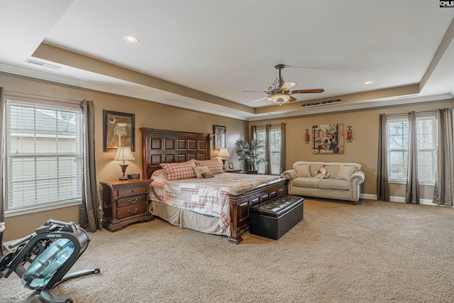 bedroom with ceiling fan, light carpet, and a raised ceiling