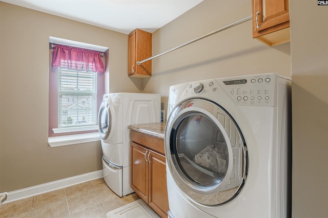 laundry area with cabinets, light tile floors, and washer and dryer