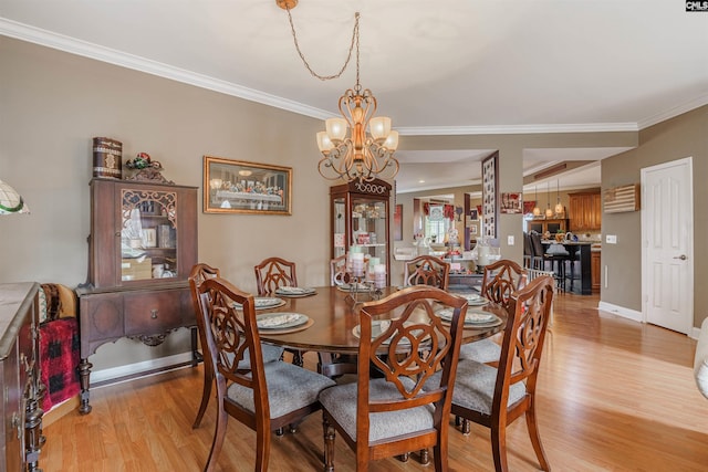 dining space with crown molding, light hardwood / wood-style flooring, and a chandelier