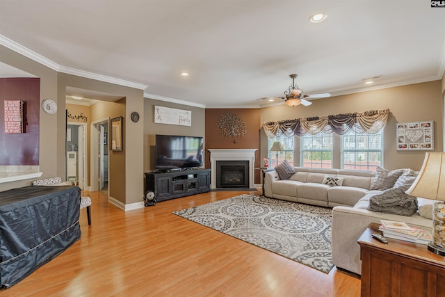 living room with crown molding, light hardwood / wood-style floors, and ceiling fan