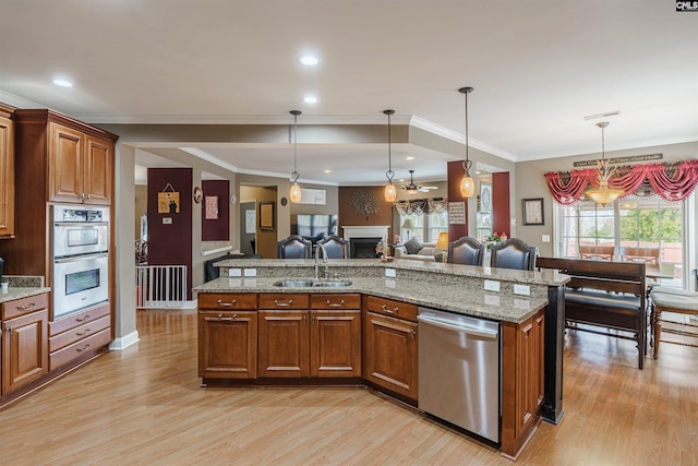 kitchen with appliances with stainless steel finishes, pendant lighting, sink, and light wood-type flooring