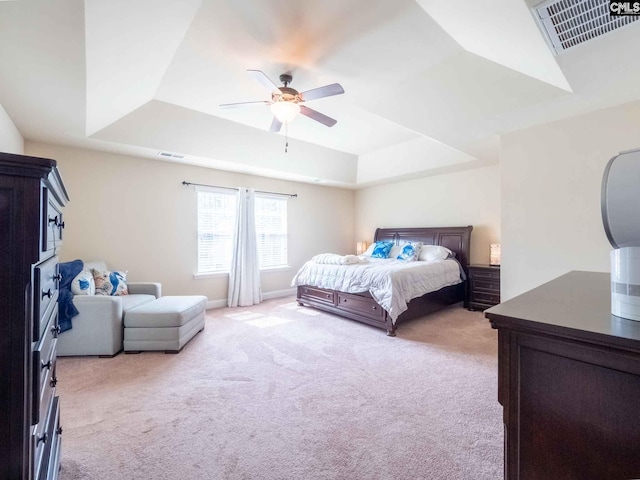 bedroom featuring a raised ceiling, ceiling fan, and light carpet