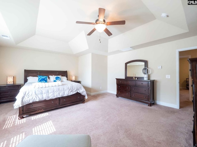 carpeted bedroom with a raised ceiling and ceiling fan