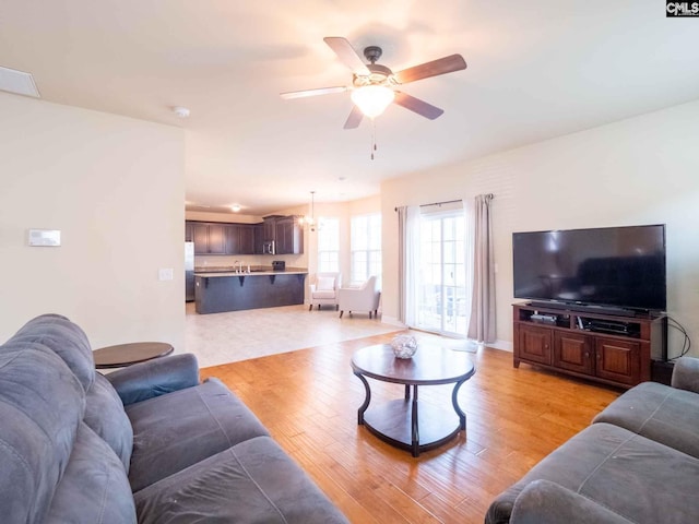 living room featuring ceiling fan with notable chandelier and light tile floors