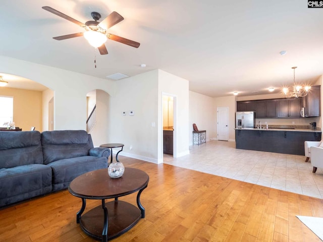 living room featuring ceiling fan with notable chandelier, sink, and light tile floors