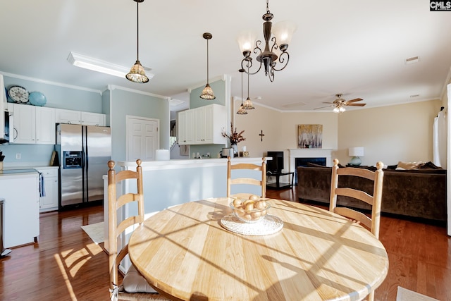 dining area with dark hardwood / wood-style flooring, crown molding, and ceiling fan with notable chandelier