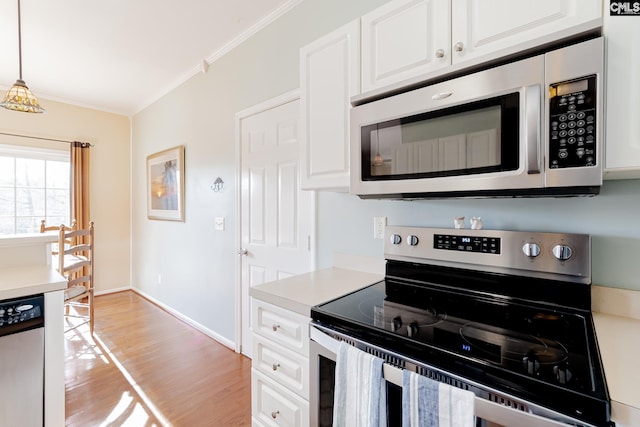 kitchen with white cabinetry, appliances with stainless steel finishes, light hardwood / wood-style floors, pendant lighting, and ornamental molding