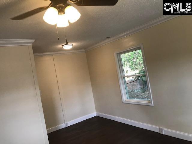 unfurnished room featuring ceiling fan, crown molding, a textured ceiling, and dark hardwood / wood-style flooring