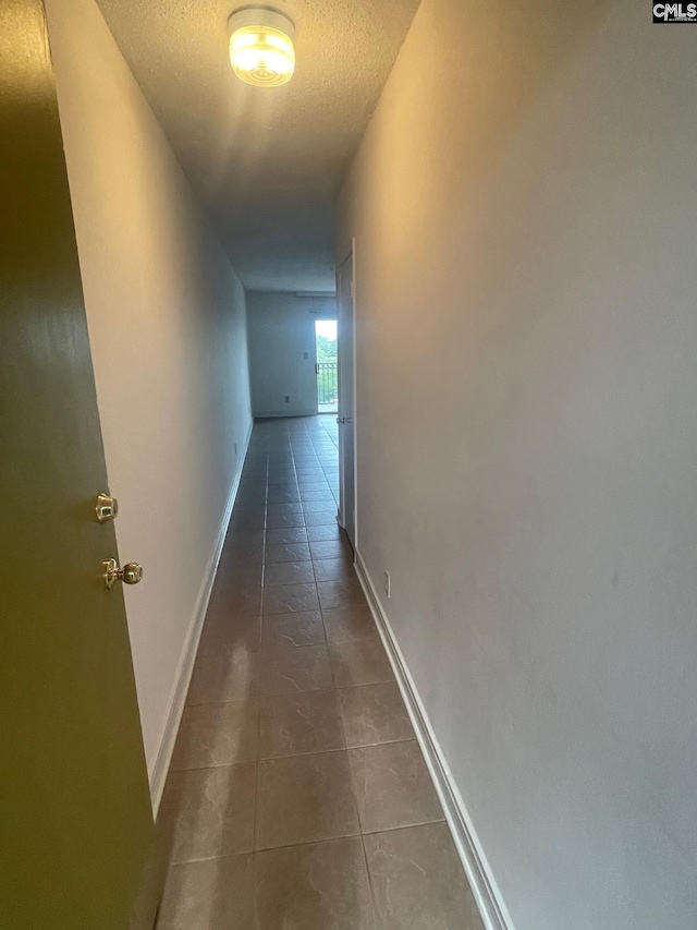 corridor with a textured ceiling and dark tile flooring