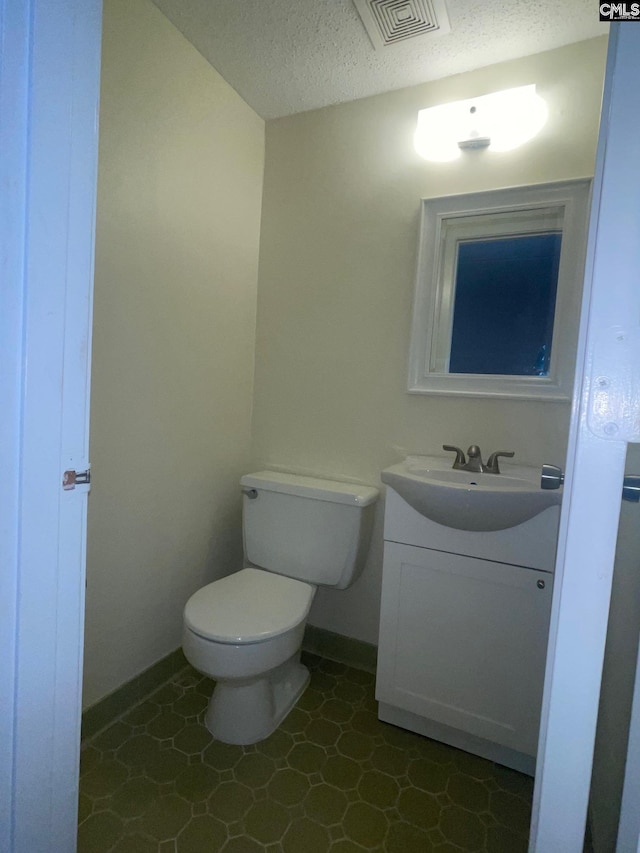 bathroom featuring tile floors, toilet, vanity, and a textured ceiling