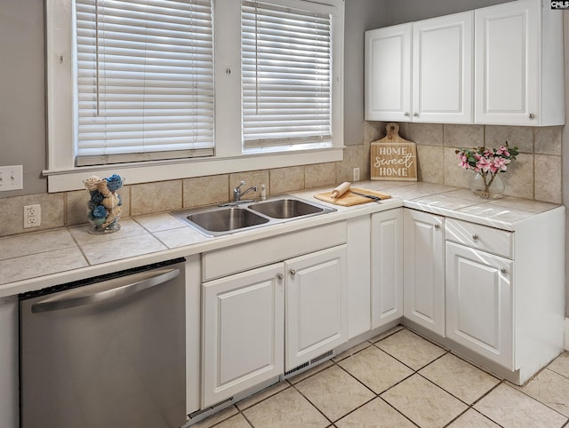 kitchen with white cabinetry, sink, light tile floors, stainless steel dishwasher, and tasteful backsplash