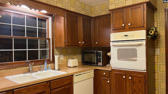 kitchen with backsplash, white appliances, and sink