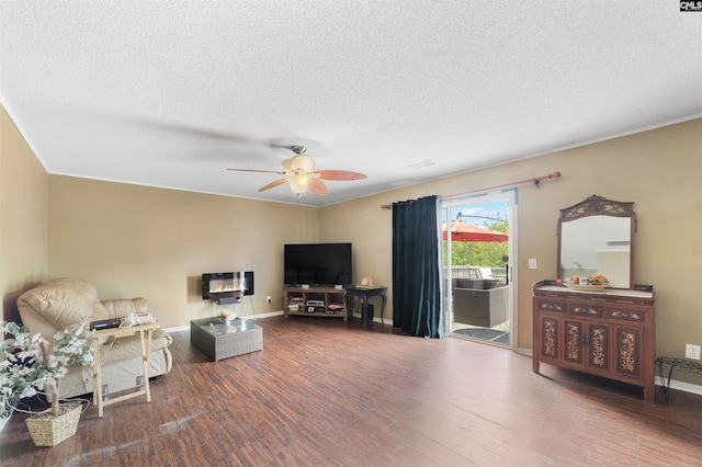 living room featuring dark hardwood / wood-style flooring, ceiling fan, and a textured ceiling