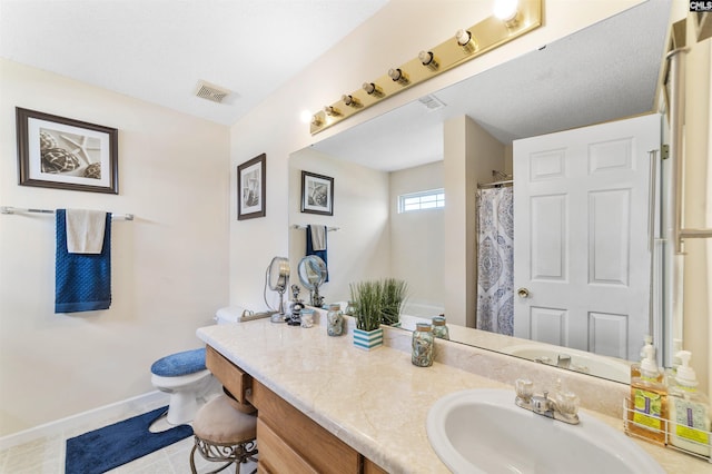 bathroom featuring oversized vanity, tile flooring, toilet, and a textured ceiling