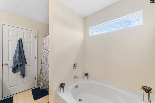 bathroom featuring tile flooring, a bathing tub, and a textured ceiling