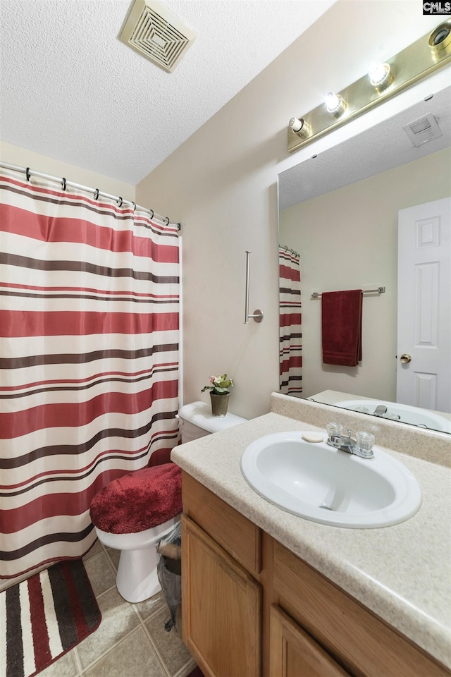 bathroom featuring a textured ceiling, tile floors, large vanity, and toilet