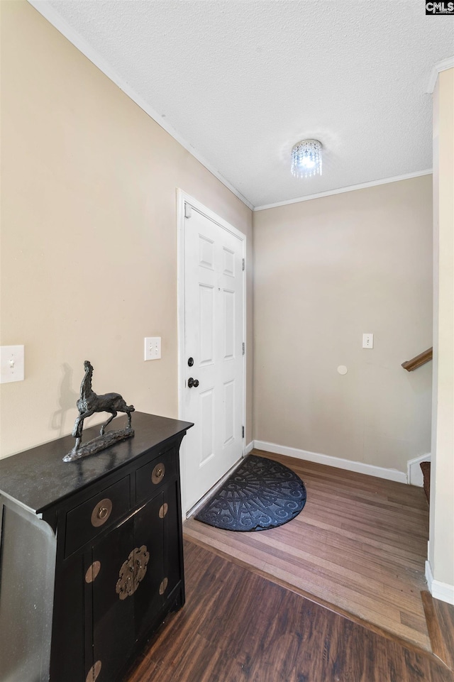 foyer with crown molding, dark hardwood / wood-style floors, and a textured ceiling