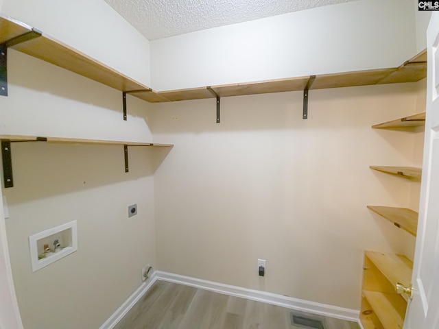 laundry area featuring hookup for an electric dryer, a textured ceiling, hardwood / wood-style flooring, and hookup for a washing machine