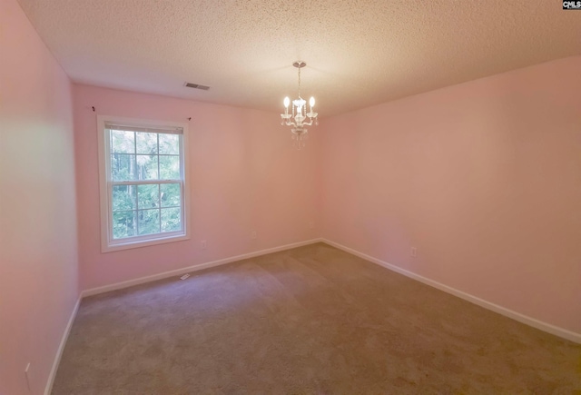 carpeted spare room with a textured ceiling and a chandelier