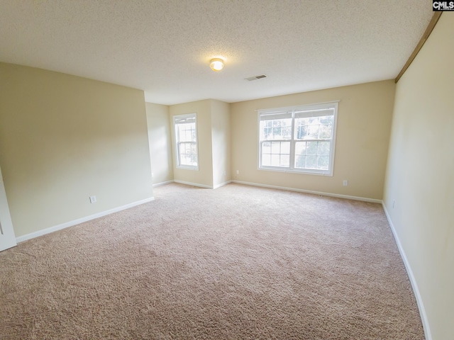 carpeted empty room featuring a textured ceiling