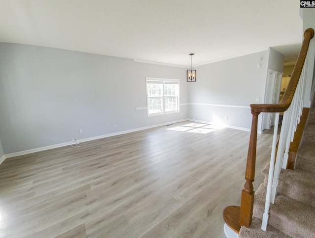 spare room featuring crown molding, light hardwood / wood-style flooring, and an inviting chandelier