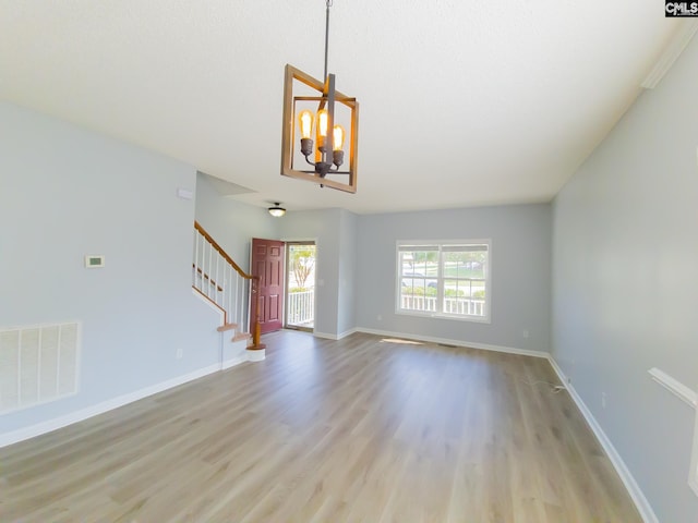 spare room with a chandelier and light hardwood / wood-style floors