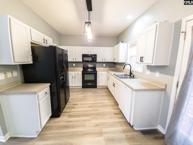 kitchen with decorative light fixtures, white cabinets, light hardwood / wood-style flooring, black appliances, and sink