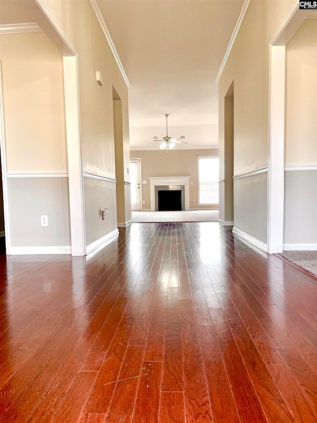 unfurnished living room with ornamental molding, ceiling fan, and dark hardwood / wood-style flooring