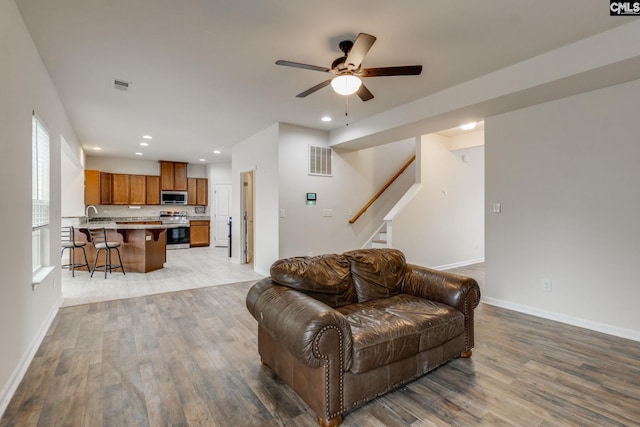 living room featuring ceiling fan, sink, and light hardwood / wood-style flooring