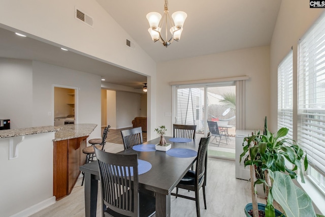 dining room with ceiling fan with notable chandelier and lofted ceiling