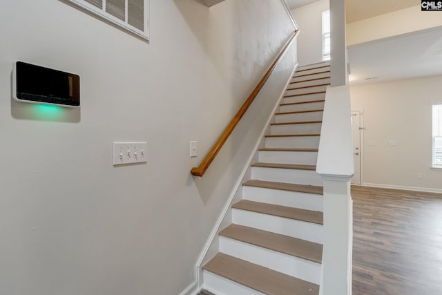 stairway with a healthy amount of sunlight and hardwood / wood-style floors